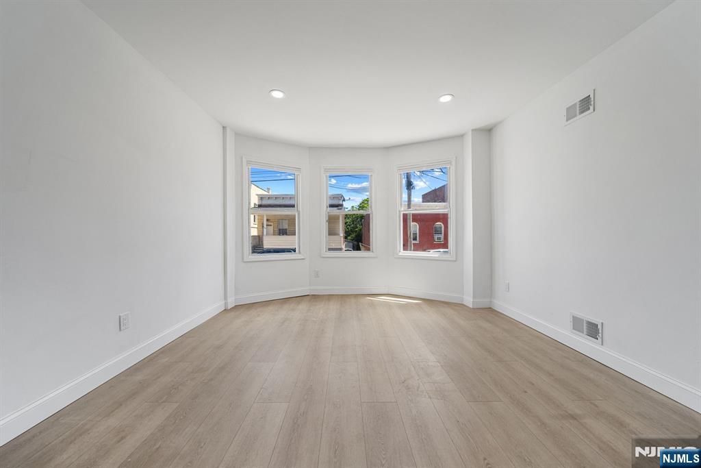 61 Farnham Avenue, Unit 1 Garfield, NJ 07026 - Photo 5 of 14 an empty room with wooden floor and windows