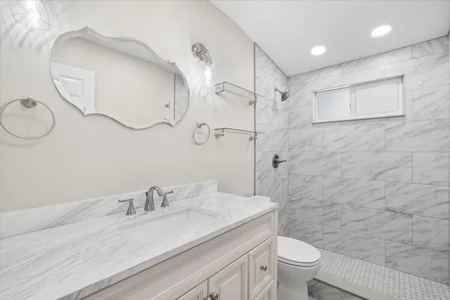 a bathroom with a granite countertop sink a toilet and a mirror