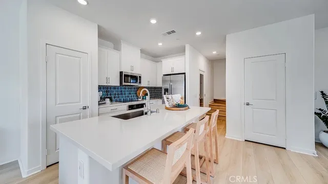 a kitchen with kitchen island a stove a sink a refrigerator and a cabinets