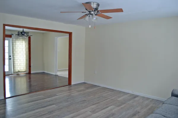 an empty room with wooden floor closet and windows