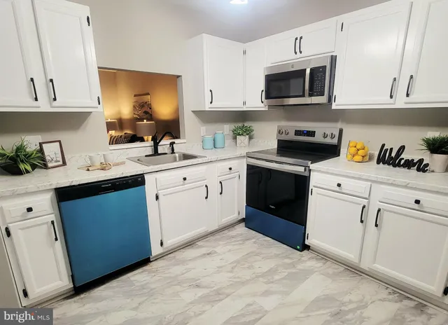a kitchen with cabinets stainless steel appliances and sink