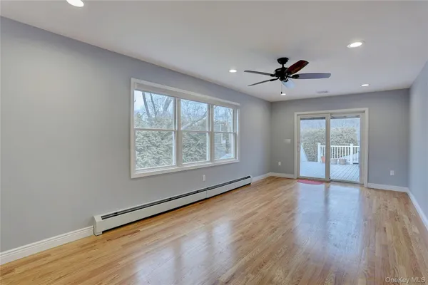 a view of an empty room with a window and wooden floor