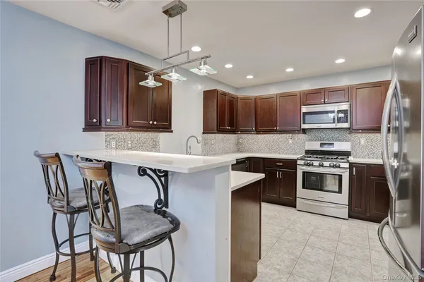 a kitchen with stainless steel appliances granite countertop a stove top oven a sink and a refrigerator