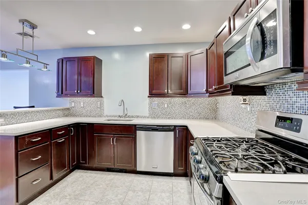 a kitchen with stainless steel appliances granite countertop a stove a sink and a microwave