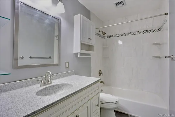 a bathroom with a granite countertop sink a toilet and shower