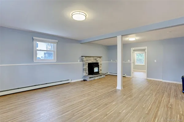 an empty room with wooden floor fireplace and windows