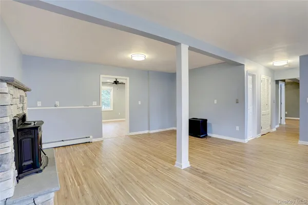 a view of an empty room with wooden floor and kitchen