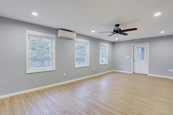 a view of an empty room with a window and wooden floor