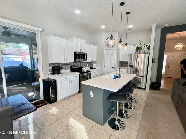 a kitchen with stainless steel appliances kitchen island a table chairs microwave and sink