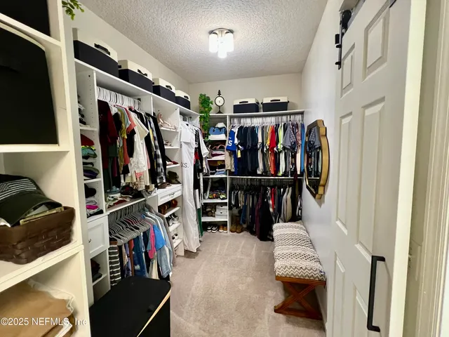a view of walk in closet with clothes and shoes