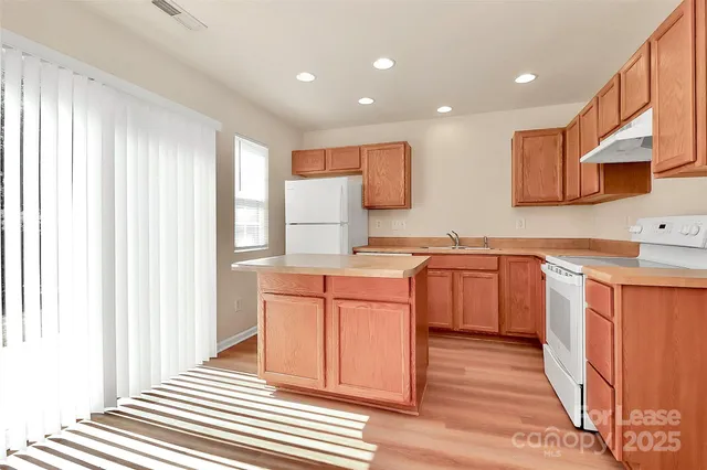 a kitchen with stainless steel appliances granite countertop a sink a stove a refrigerator and cabinets