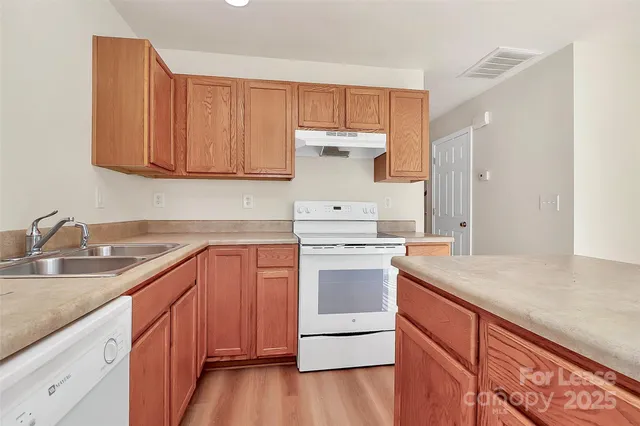 a kitchen with granite countertop wooden cabinets and white appliances