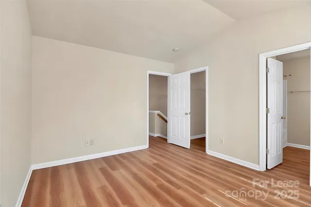 a view of an empty room with wooden floor and closet