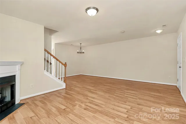 a view of an empty room with wooden floor and a fireplace