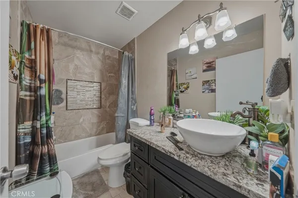a bathroom with a granite countertop sink toilet a mirror and shower