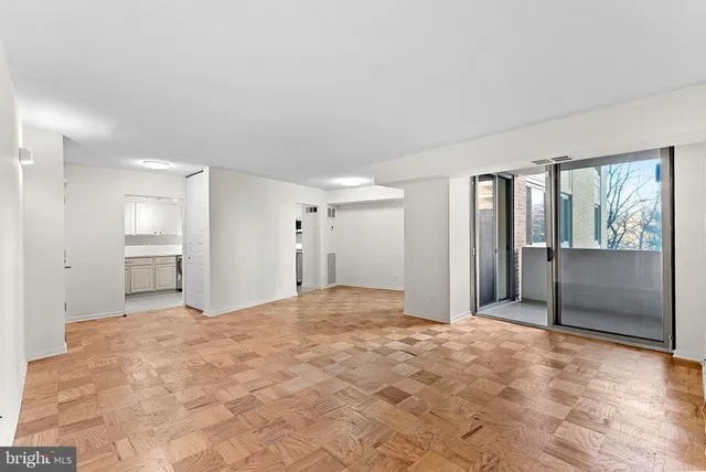 a view of an empty room with window and wooden floor