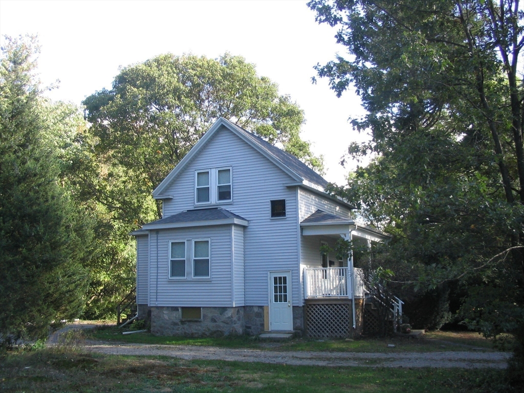 a view of a yard in front of a house with plants and large tree