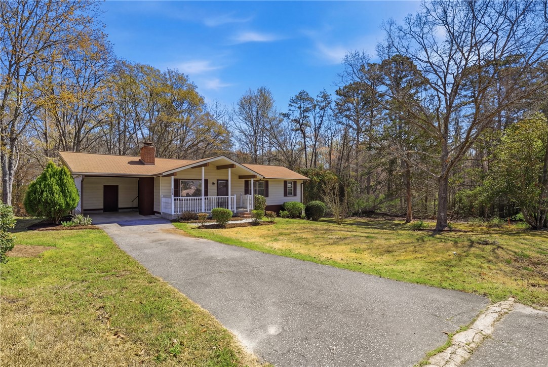 410 Springdale Avenue Liberty, SC 29657 - Photo 26 of 50 This charming home features a welcoming porch and a long driveway, nestled amidst lush trees.