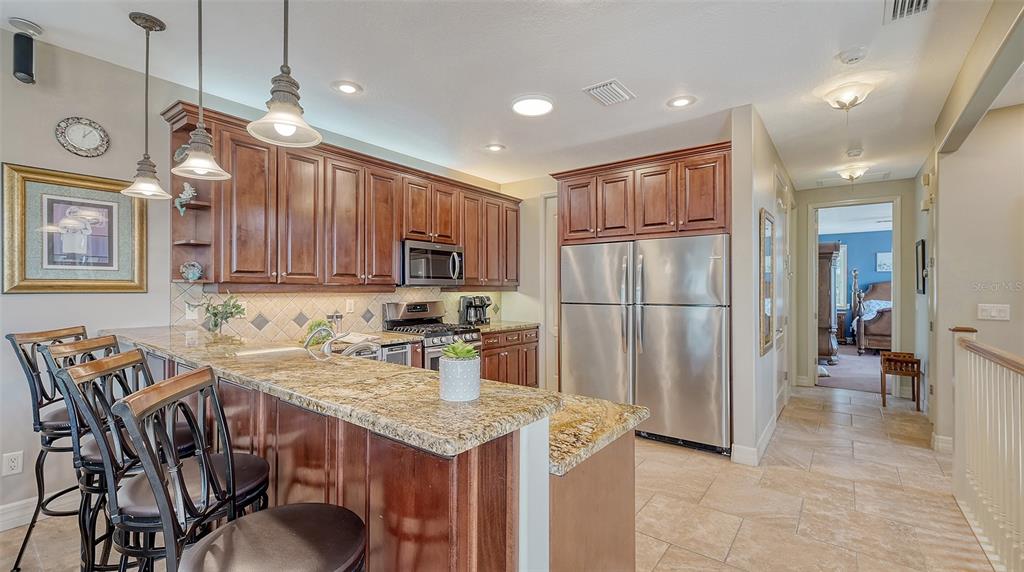 220 36th Street Holmes Beach, FL 34217 - Photo 16 of 59 a kitchen with stainless steel appliances granite countertop a table chairs and a refrigerator