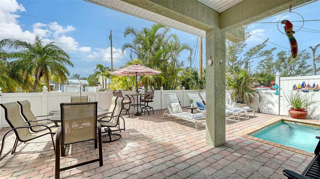 220 36th Street Holmes Beach, FL 34217 - Photo 31 of 59 a view of a patio with a table and chairs under an umbrella with potted plants