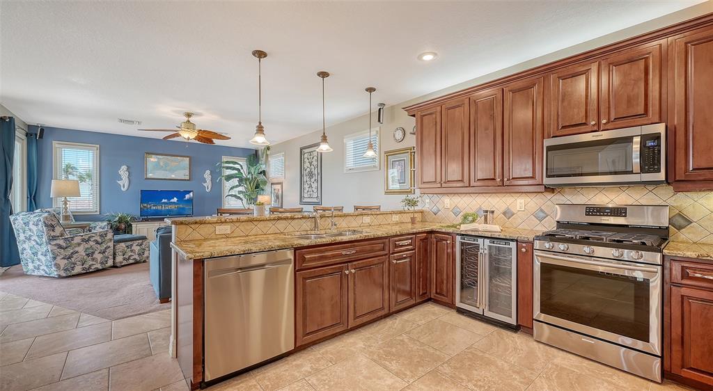 220 36th Street Holmes Beach, FL 34217 - Photo 9 of 59 a kitchen with stainless steel appliances granite countertop a stove top oven a sink dishwasher a dining table and chairs with wooden floor
