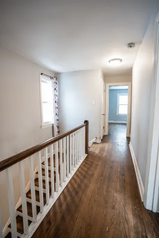 a view of a hallway with wooden floor and windows