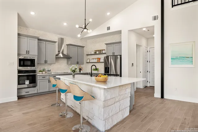 a kitchen with stainless steel appliances granite countertop a sink a stove and a refrigerator