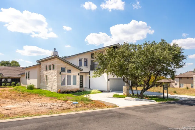 a backyard of a house with plants and large tree
