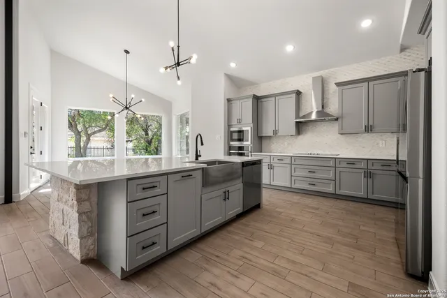 a kitchen with stainless steel appliances kitchen island granite countertop a stove a sink and a refrigerator