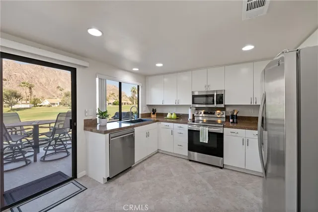 a kitchen with stainless steel appliances granite countertop a stove top oven a sink and a refrigerator