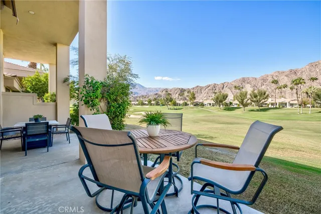 a view of a chairs and table in patio next to a yard