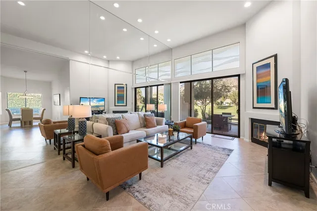 a living room with furniture kitchen view and large windows