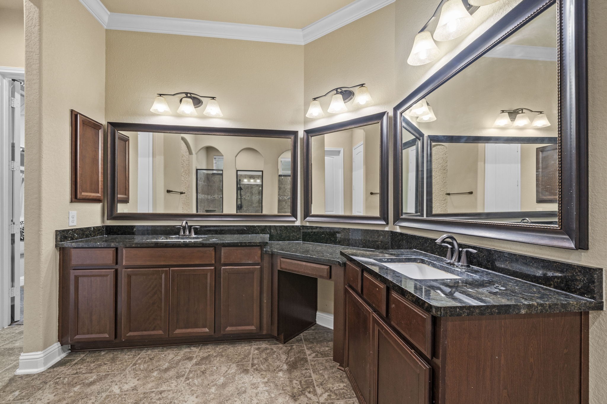 14215 Spindle Arbor Road Cypress, TX 77429 - Photo 5 of 47 This bathroom features dual sinks with dark granite countertops, ample wooden cabinetry, large mirrors, and stylish lighting, creating a spacious and elegant feel.