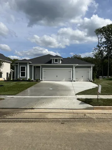 a view of house with a garden and parking space