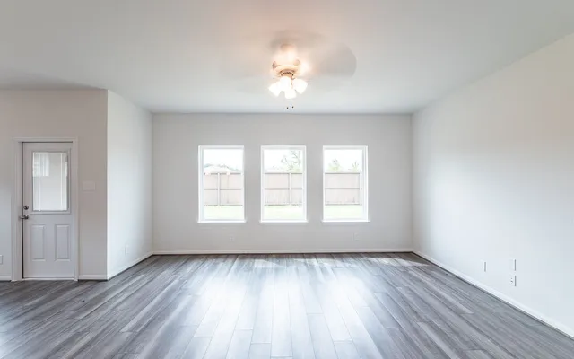 an empty room with wooden floor and windows