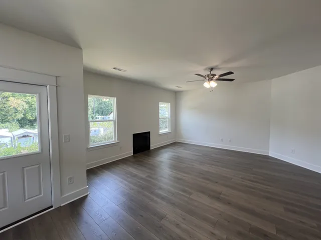 a view of an empty room with a window and wooden floor