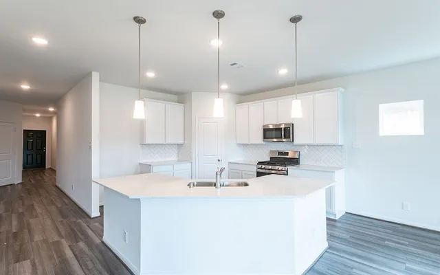 a kitchen with kitchen island a sink and a stove top oven with wooden floor