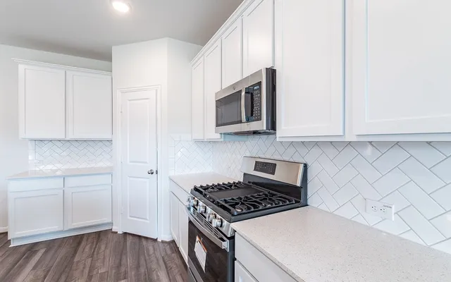a kitchen with stainless steel appliances a white cabinet and a stove top oven