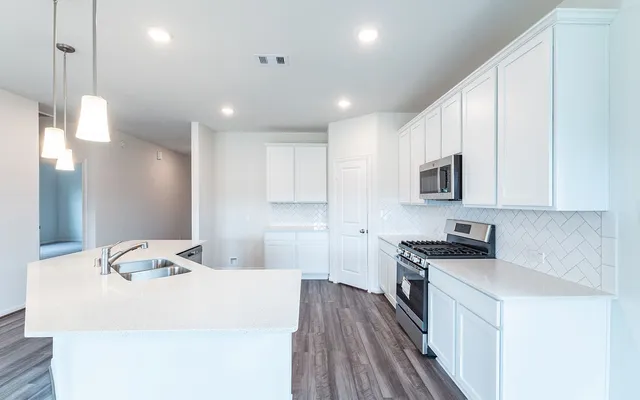 a kitchen with kitchen island a sink stainless steel appliances and cabinets