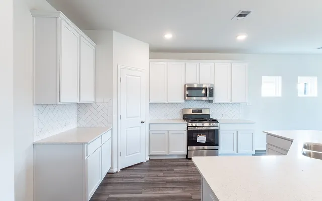 a kitchen with granite countertop white cabinets and stainless steel appliances
