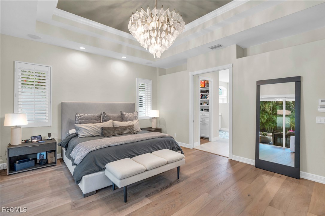 11451 Compass Point Drive Fort Myers, FL 33908 - Photo 21 of 47 a spacious bedroom with a bed a table and a chandelier