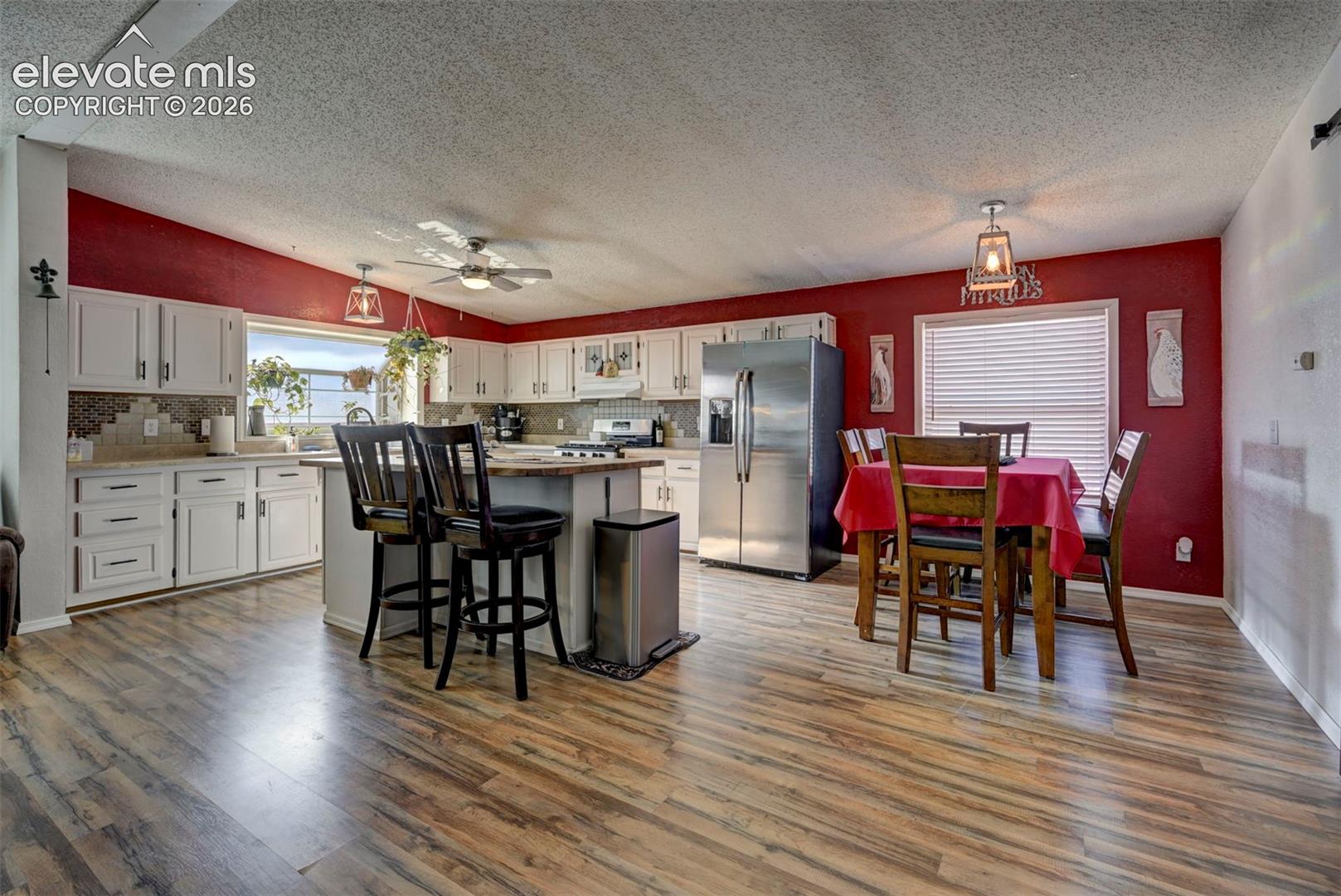 35355 Funk Road Calhan, CO 80808 - Photo 10 of 31 Kitchen with white cabinets, stainless steel appliances, a textured ceiling, light wood-style floors, and a breakfast bar area