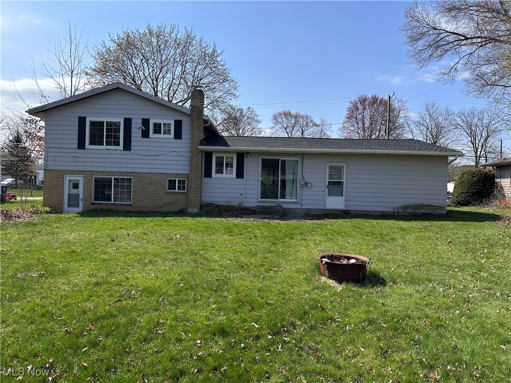 2829 Shellhart Road Barberton, OH 44203 - Photo 27 of 29 Rear view of house with an outdoor fire pit, a chimney, brick siding, and a yard