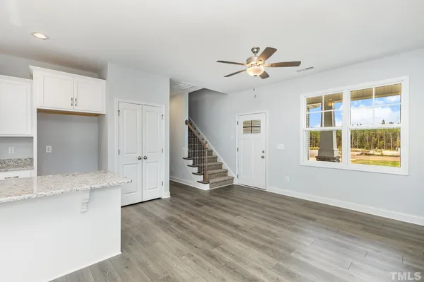 a view of an empty room with window ceiling fan and wooden floor