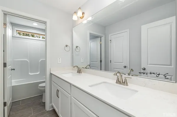 a bathroom with a sink double vanity granite tub shower and a mirror