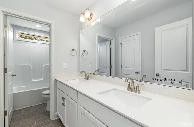 a bathroom with a sink double vanity granite tub shower and a mirror