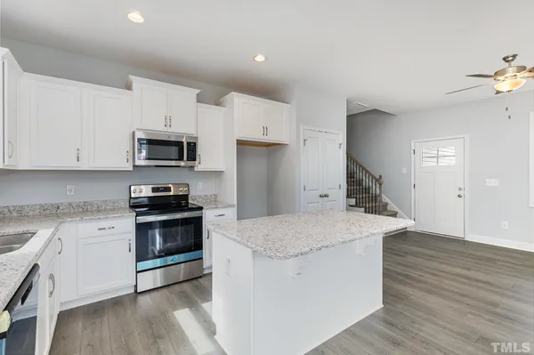 a kitchen with granite countertop a sink wooden floor and stainless steel appliances