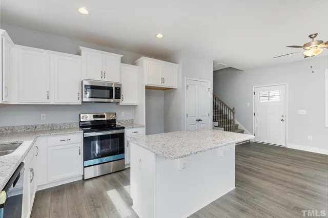 a kitchen with granite countertop a sink wooden floor and stainless steel appliances