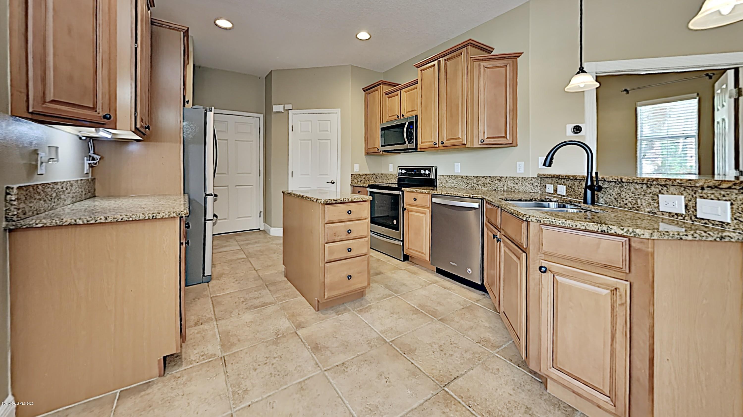 830 Riviera Drive Northeast Palm Bay, FL 32905 - Photo 5 of 21 a kitchen with stainless steel appliances granite countertop a stove sink and cabinets