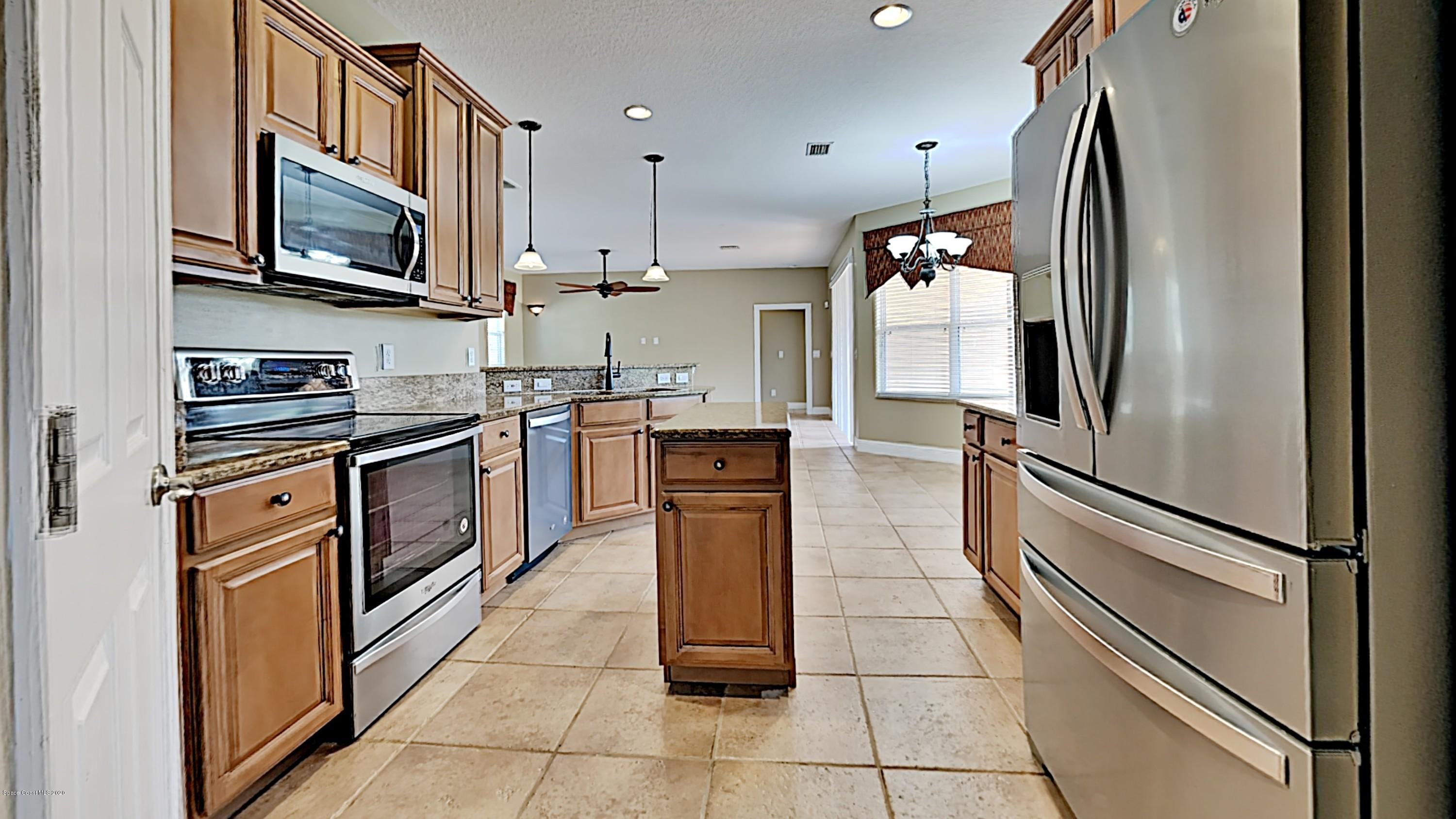 830 Riviera Drive Northeast Palm Bay, FL 32905 - Photo 6 of 21 a kitchen with stainless steel appliances granite countertop a refrigerator a stove and a sink